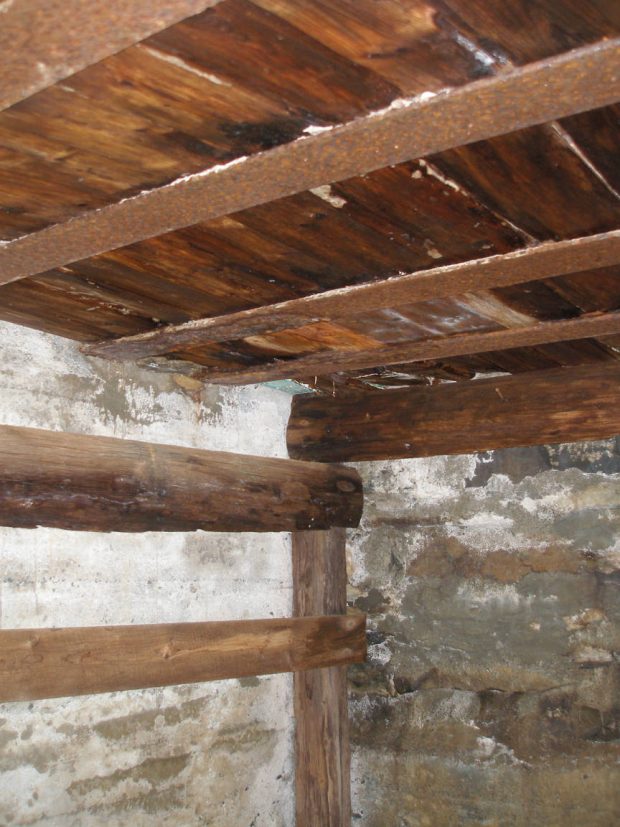 Detail of 4 iron railroad tracks used to support wooden roof.