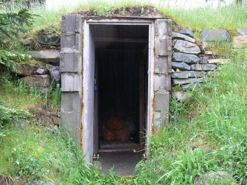 Rectangular concrete door with stacked stone to a hill side root cellar.