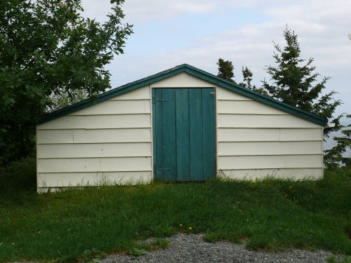 White root cellar top shed with a blue wooden door.