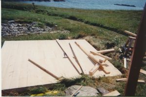 Top view of the top shed floor of the root cellar under construction in a grassy field by the ocean.