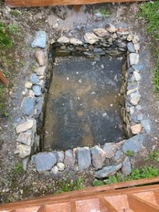 Top view of a rectangular hole walled with stacked stone.