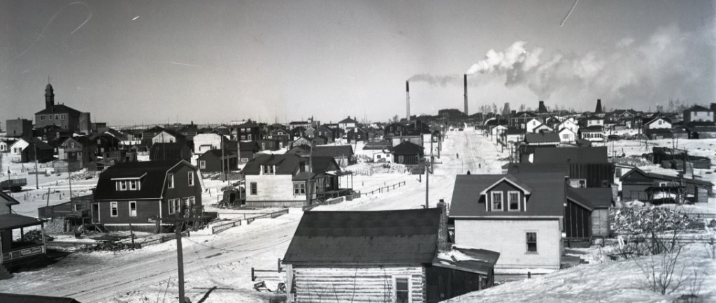 Photographie en noir et blanc de la rue Galipeau maintenant Larivière. En arrière-plan : l'hôtel de ville de Rouyn à gauche et la mine Horne à droite.