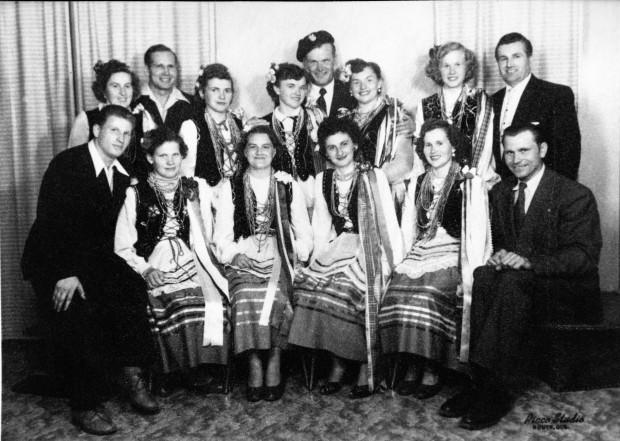 Black-and-white photograph of 14 people, nine of whom are dressed in traditional Ukrainian clothing with five men in dapper suits.