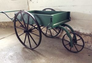 Colour photo of a green handcart with one small front wheel and two large rear wheels.