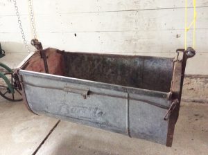 Colour photo of a large metal bucket hanging from a chain and rope.