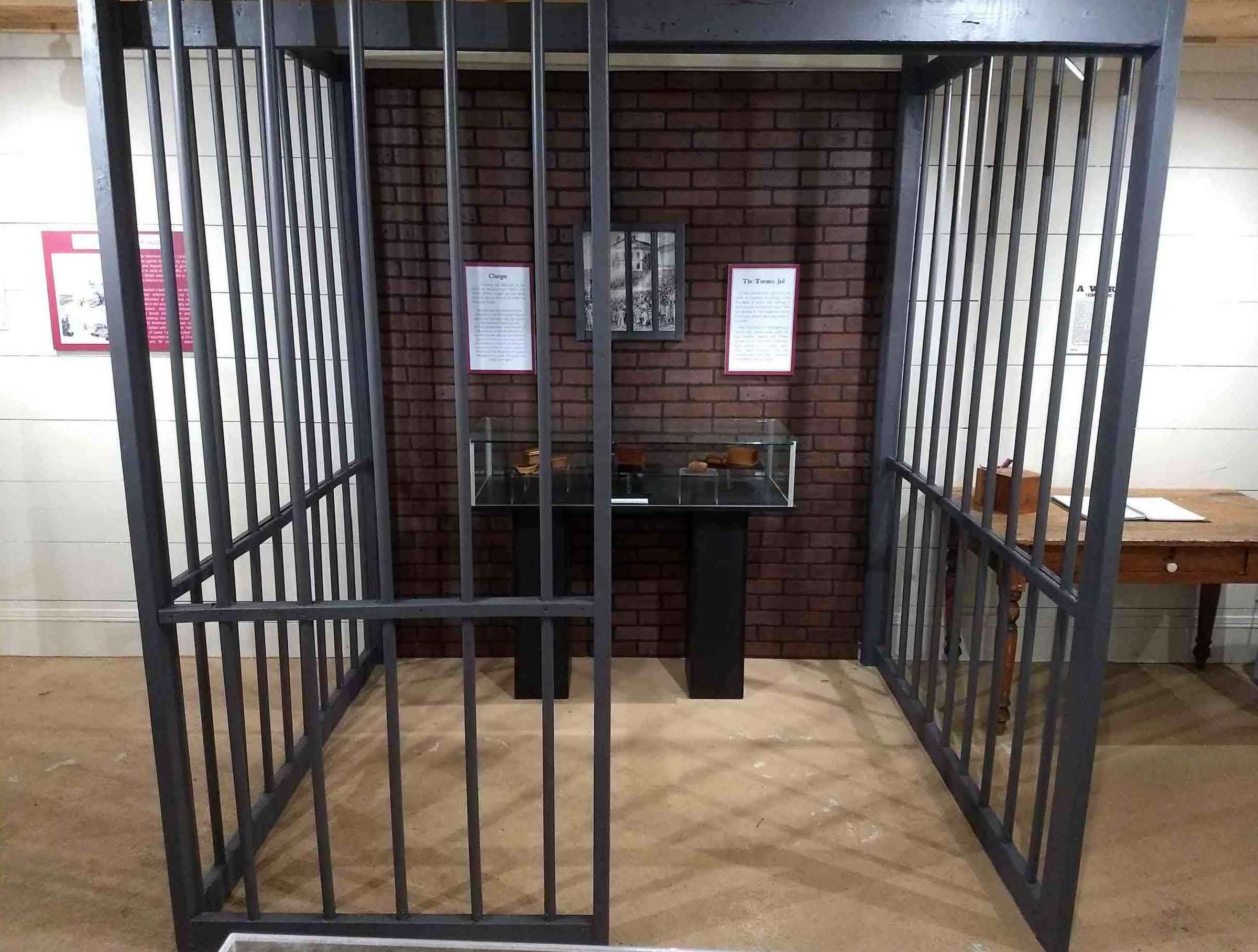 Photo de la réplique d’une cellule de prison qui se trouve dans la salle d’exposition du temple de Sharon. Les visiteurs peuvent entrer dans la cellule pour voir notre collection de coffrets de la Rébellion. 