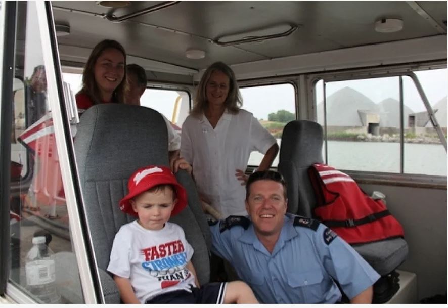 Colour photograph of five people inside a boat.