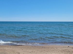 Colour photograph of a large body of water and sand.