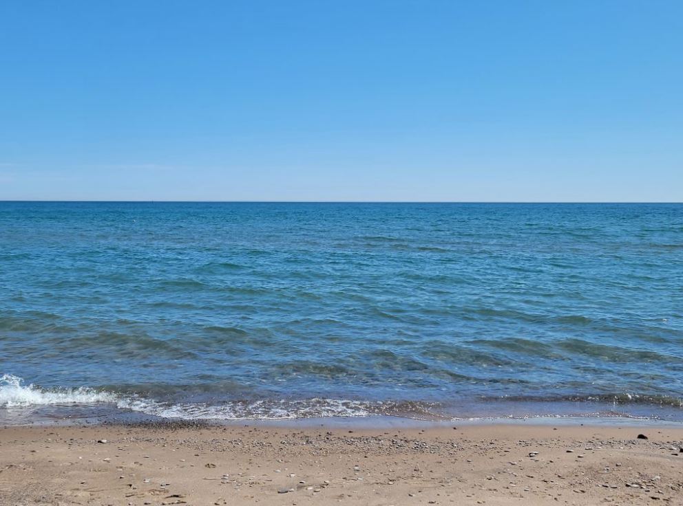 Colour photograph of a large body of water and sand.