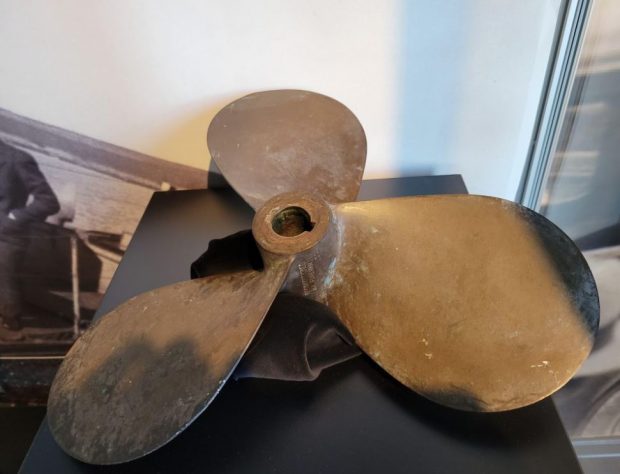 Colour photograph of a brass propeller.