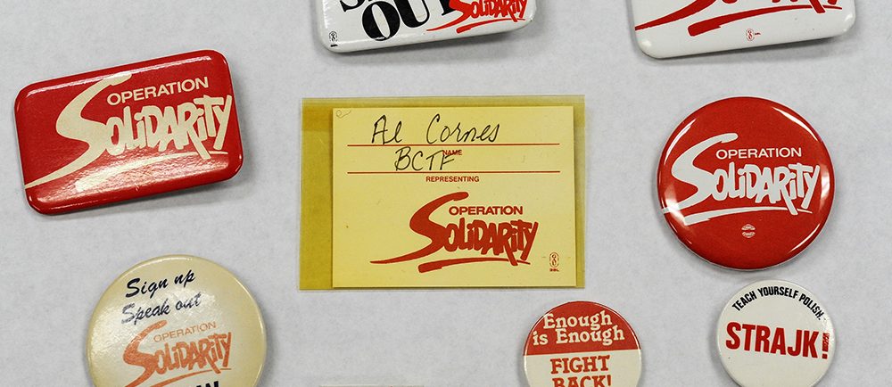 A collection of Operation Solidarity buttons, a delegate badge, and a pin from the Polish Solidarnosc union.