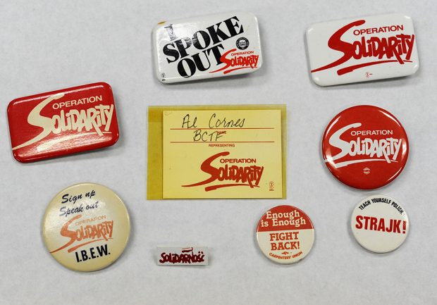 A collection of Operation Solidarity buttons, a delegate badge, and a pin from the Polish Solidarnosc union.
