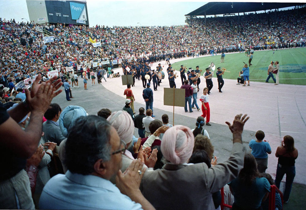 A photo shows people standing and applauding from the stadium seats as a brass band leads a lengthy parade of uniformed officers.