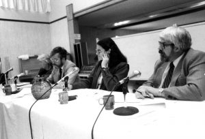Four people are seated at a table with microphones in front of them.