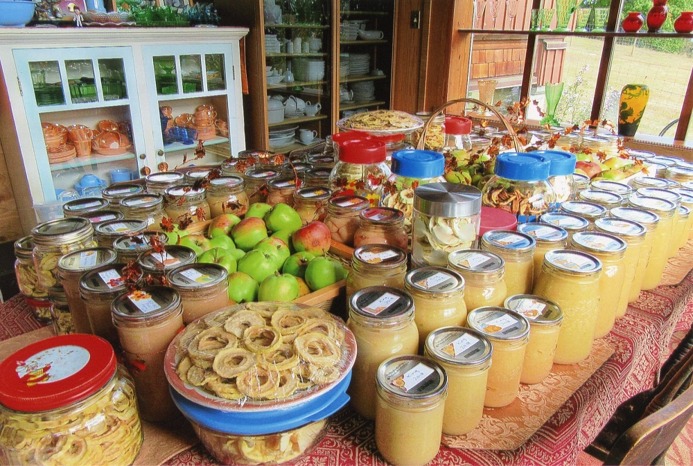 A variety of canning and fruit arranged on a farmhouse table.