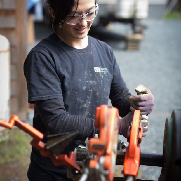 A woman operating a pipe threading machine.