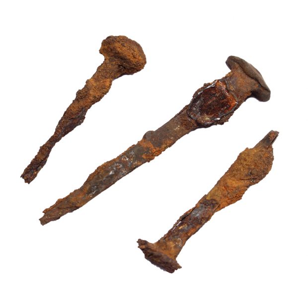 Three rusty handmade nails of varying sizes. Each have square shaped heads.