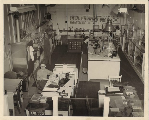 Black and white photo of the Bruck Mills laboratory with two employees at work.