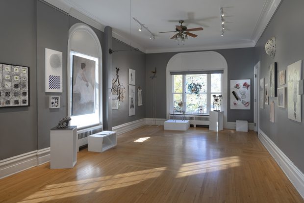 Color photo of a large room with artwork hanging on pale gray walls.