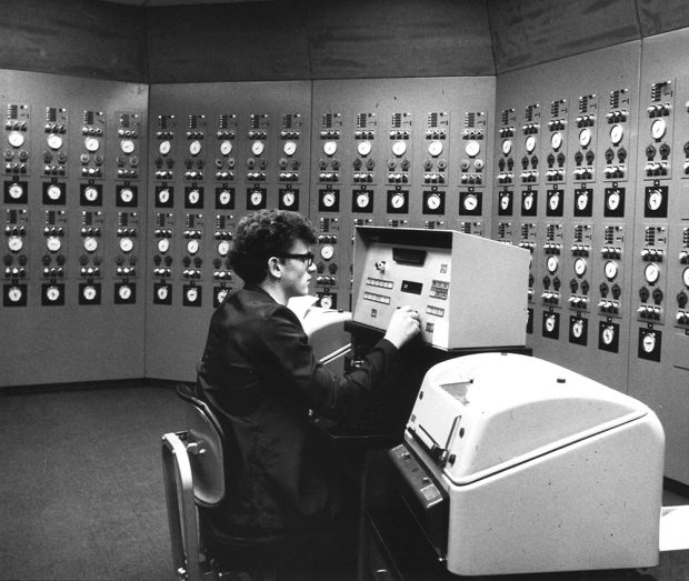 An employee sits at his workstation in a computer control room