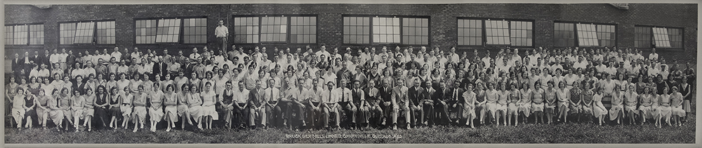 The employees and managers of the company pose in front of the factory on four rows.