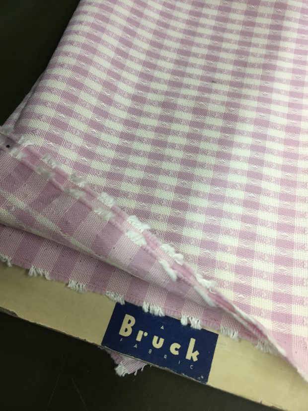 Sample of fabrics wrapped around a cardboard support identified with the Bruck Fabrics logo.