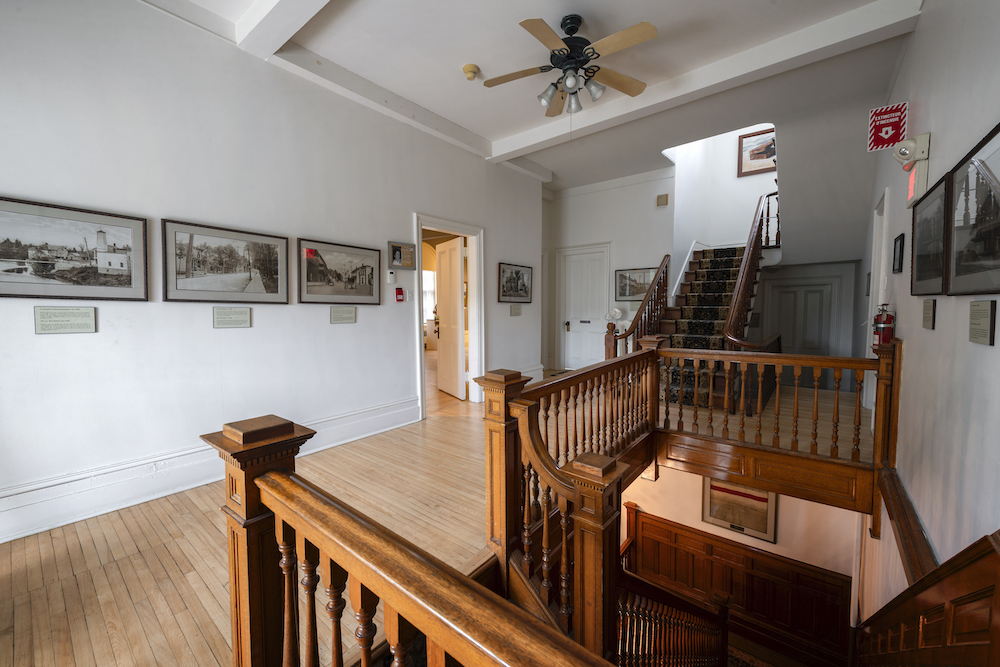 View of a room with wooden staircase and old black and white photos displayed on the walls