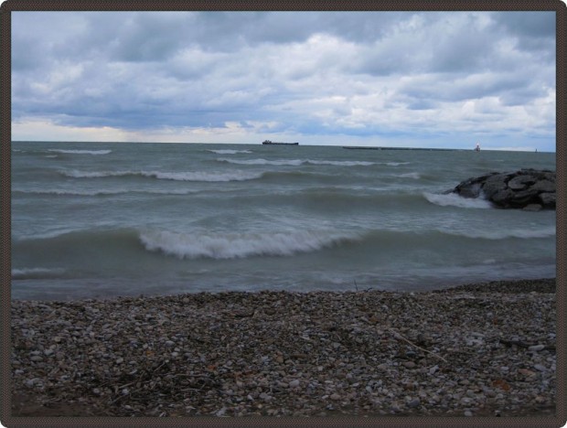 Photo taken a few feet from the water, showing the lake's waves with a large boat in the distance.