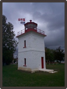 Photo d’un petit phare, au sommet duquel flotte un drapeau canadien.