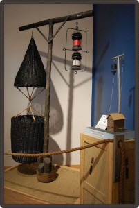 Système d’avertissement composé de paniers d’osier de différentes formes suspendus à un poteau et de lanternes de couleur suspendues.
