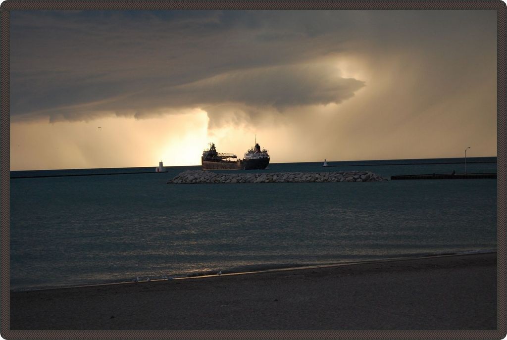 Photo taken on the lake at sunset with a lake freighter entering the harbour.
