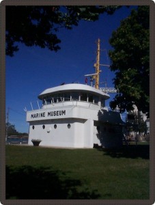 Photo du musée en été. Le musée a la forme de la passerelle d’un bateau et, à l’arrière du bâtiment, on peut voir dépassé un grand mât.