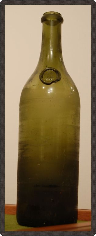 Damaged glass bottle with a seal on its neck.