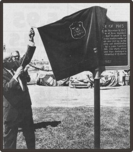 Photo en noir et blanc d’un homme retirant une housse en tissu d’une plaque.