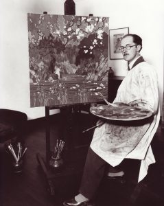 Photo noir et blanc d’un homme en blouse blanche, tenant des pinceaux et une palette, assis près d’un chevalet avec une peinture d’une jeune fille près d’une rivière.