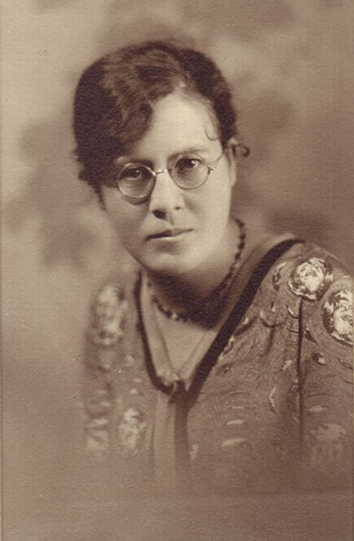 Sepia studio portrait of young woman in glasses.