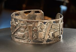 Silver cuff bracelet with abstract design in relief and cutouts.