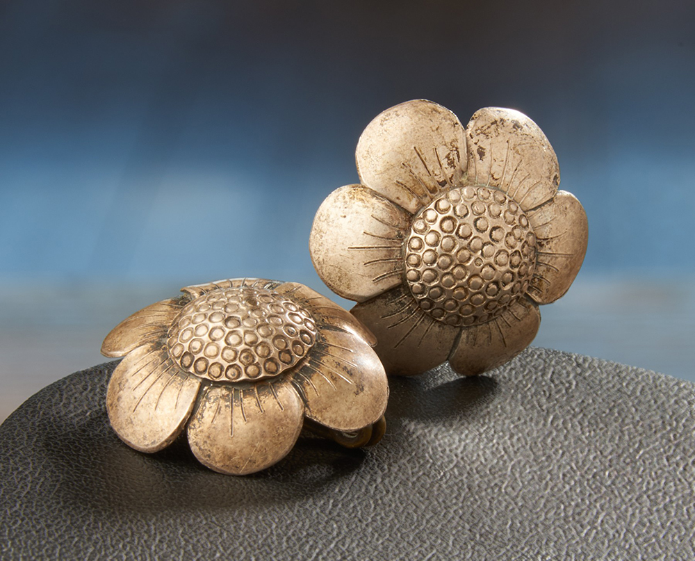 Silver earrings in the shape of small six petalled flowers.
