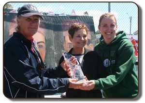 An image of The Paris Crew trophy being awarded to the two coaches of Rothesay Netherwood School in the Summer of 2017, also in the photograph is the Mayor of Rothesay, New Brunswick. The trophy is a clear crystal vase with textured decorative designed etchings. The top of the trophy is cut at an angle so the back of the trophy is higher than the front. Etched in the centre of the backside, which is made clearer by the way it was cut, has the name of the trophy.