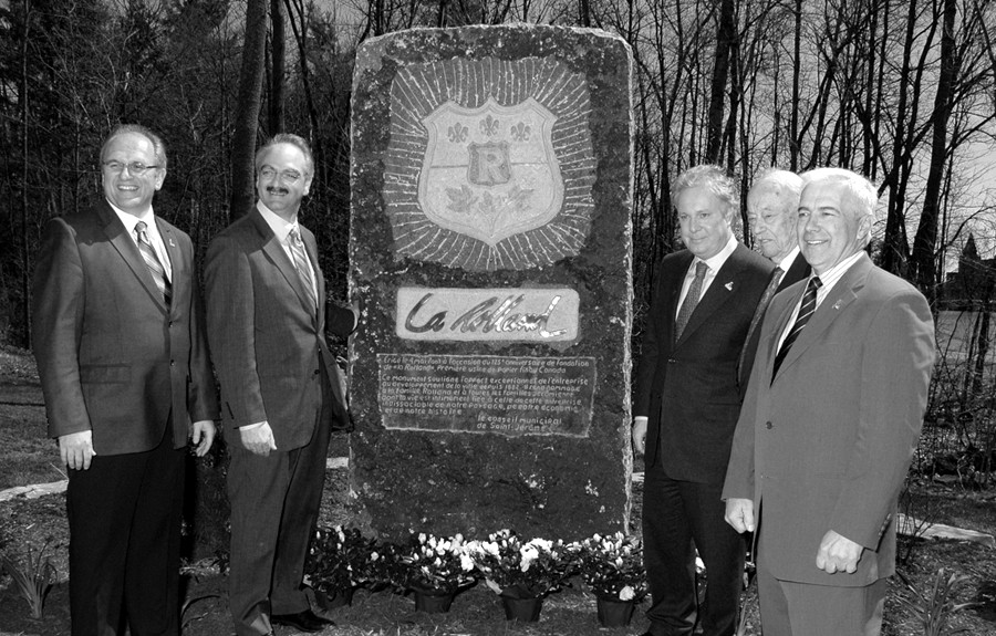 Black & white photograph of five men near a granite monument, outdoors.