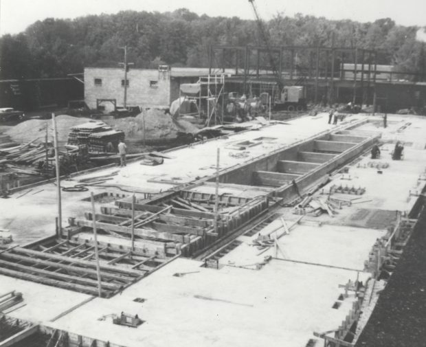 Black & white photograph of a building under construction, showing workers and machinery.