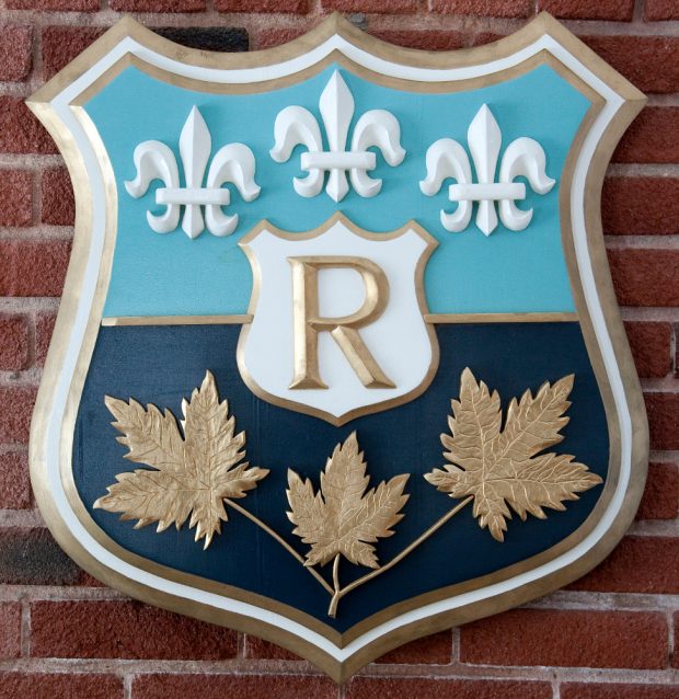 Colour photograph of the company crest engraved on a wood plaque.