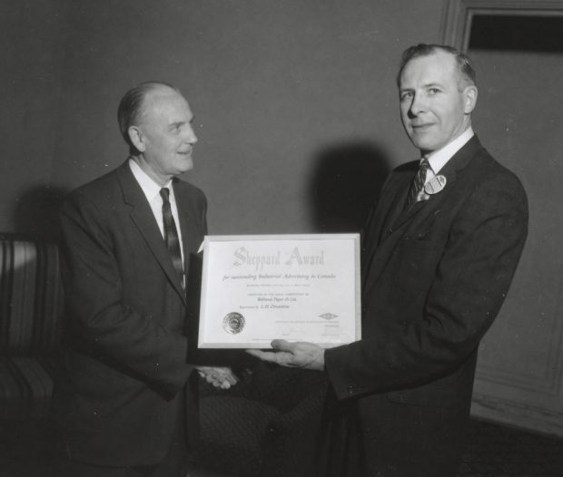 Black & white photograph of a man giving a certificate to another man as they shake hands