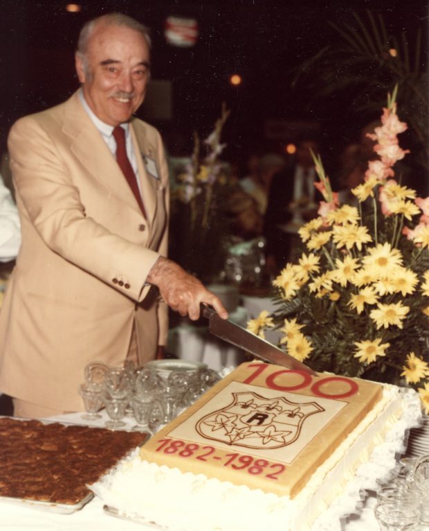 Colour photograph of an elderly man preparing to cut a cake.