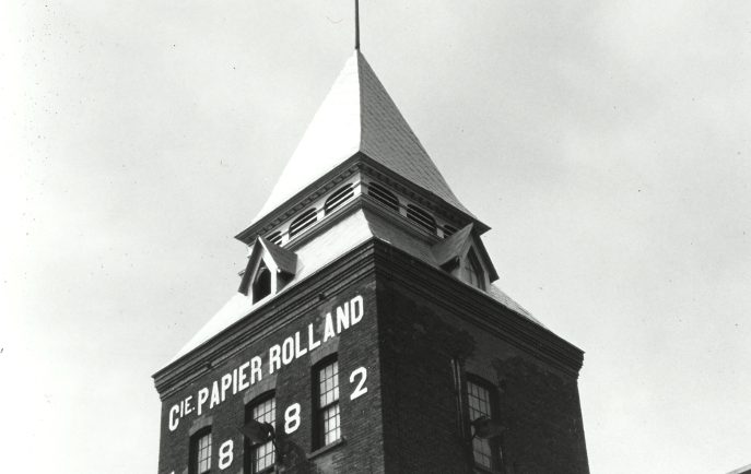 Black & white photograph showing a tower above a building.
