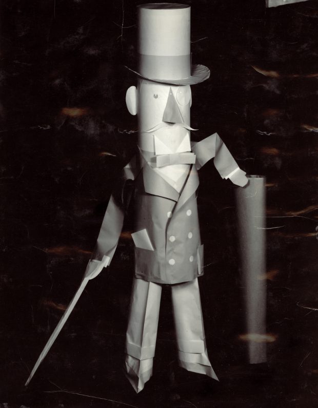 Black & white photograph of a character in a suit with a top hat made of paper.