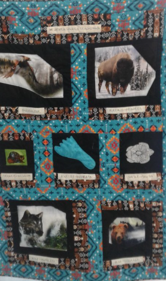 A blue quilt made with seven squares to represent the sacred animals corresponding to the seven sacred teachings.