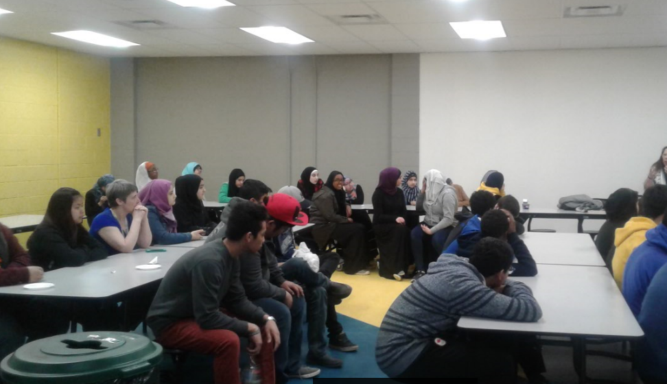 Coloured picture of group of students sitting around a square table facing front.