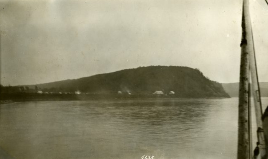 Black and white photo of a hilly land across a body of water.