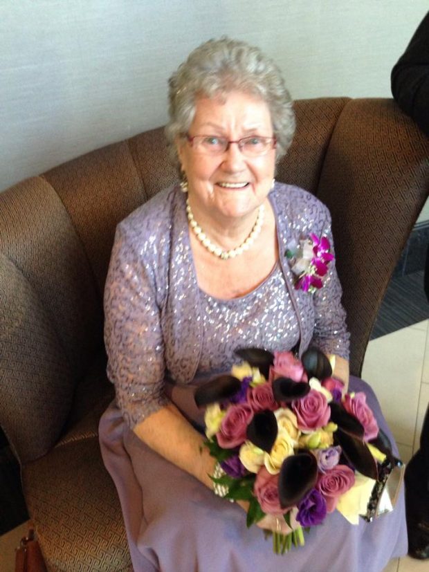 A woman dressed for a special occasion sits holding a bunch of flowers